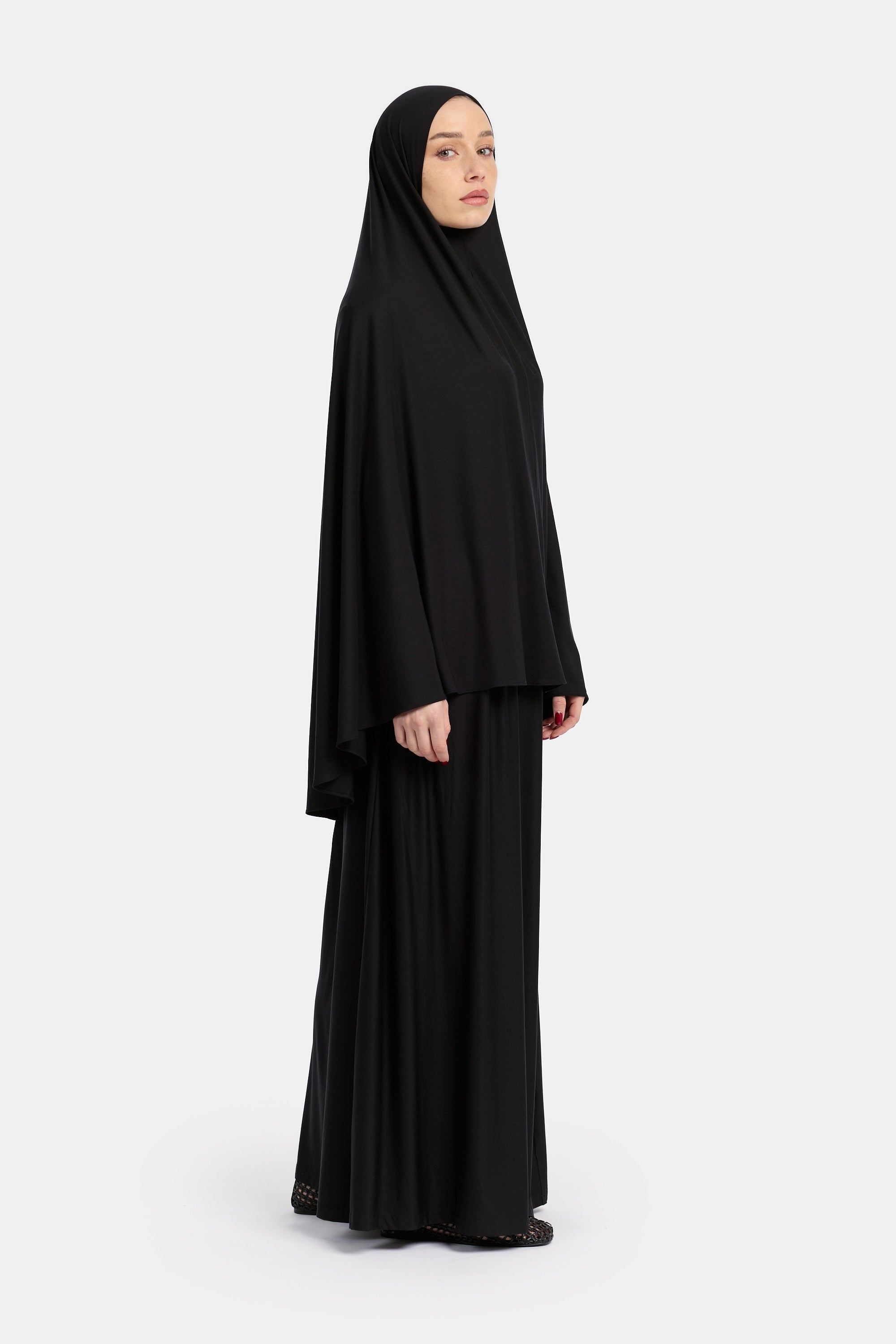 zij aanzicht van Model die draagt de breathable modal khimar en rok van de modest merk ENTI in de kleur zwart