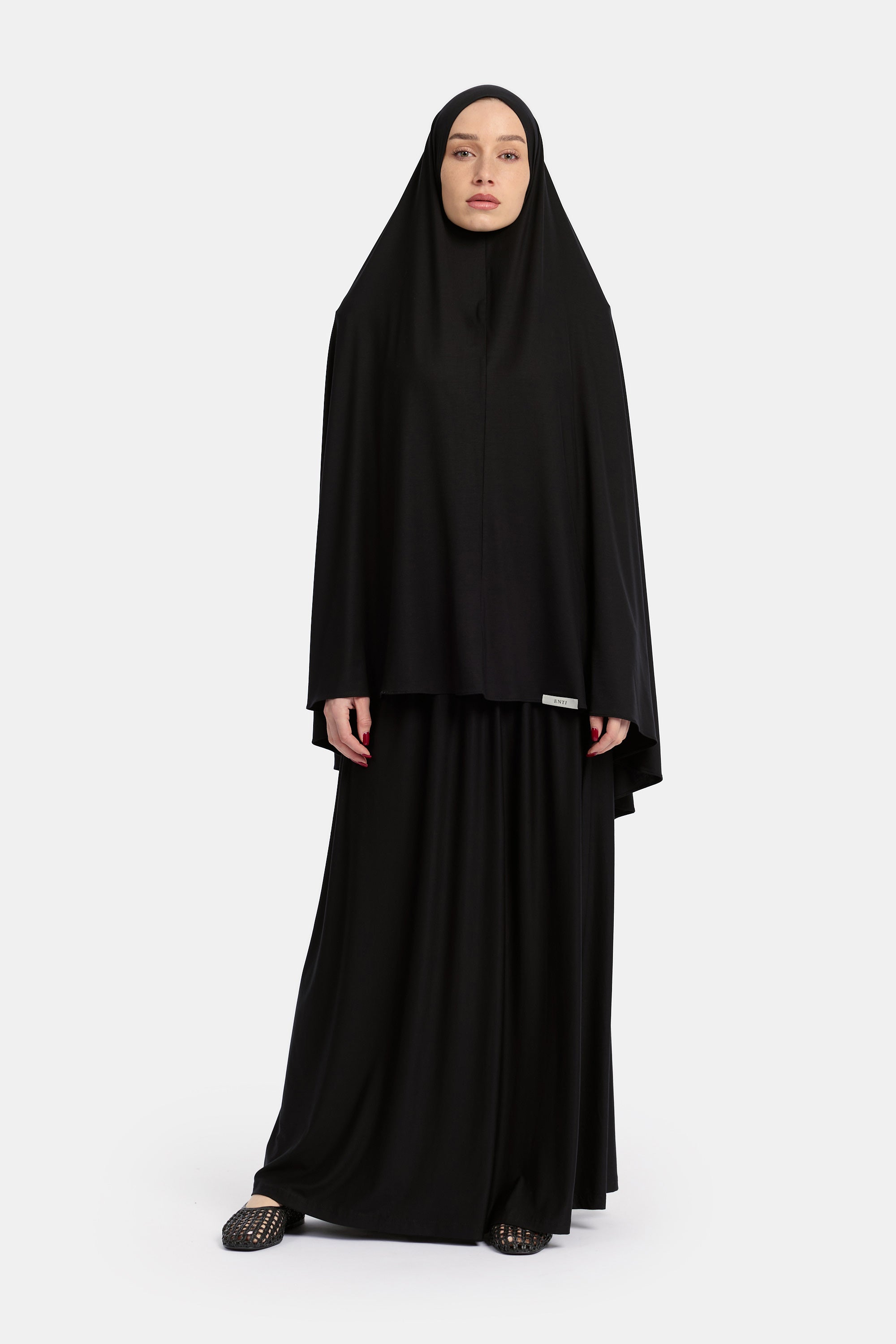 voor aanzicht van Model die draagt de breathable modal khimar en rok van de modest merk ENTI in de kleur zwart