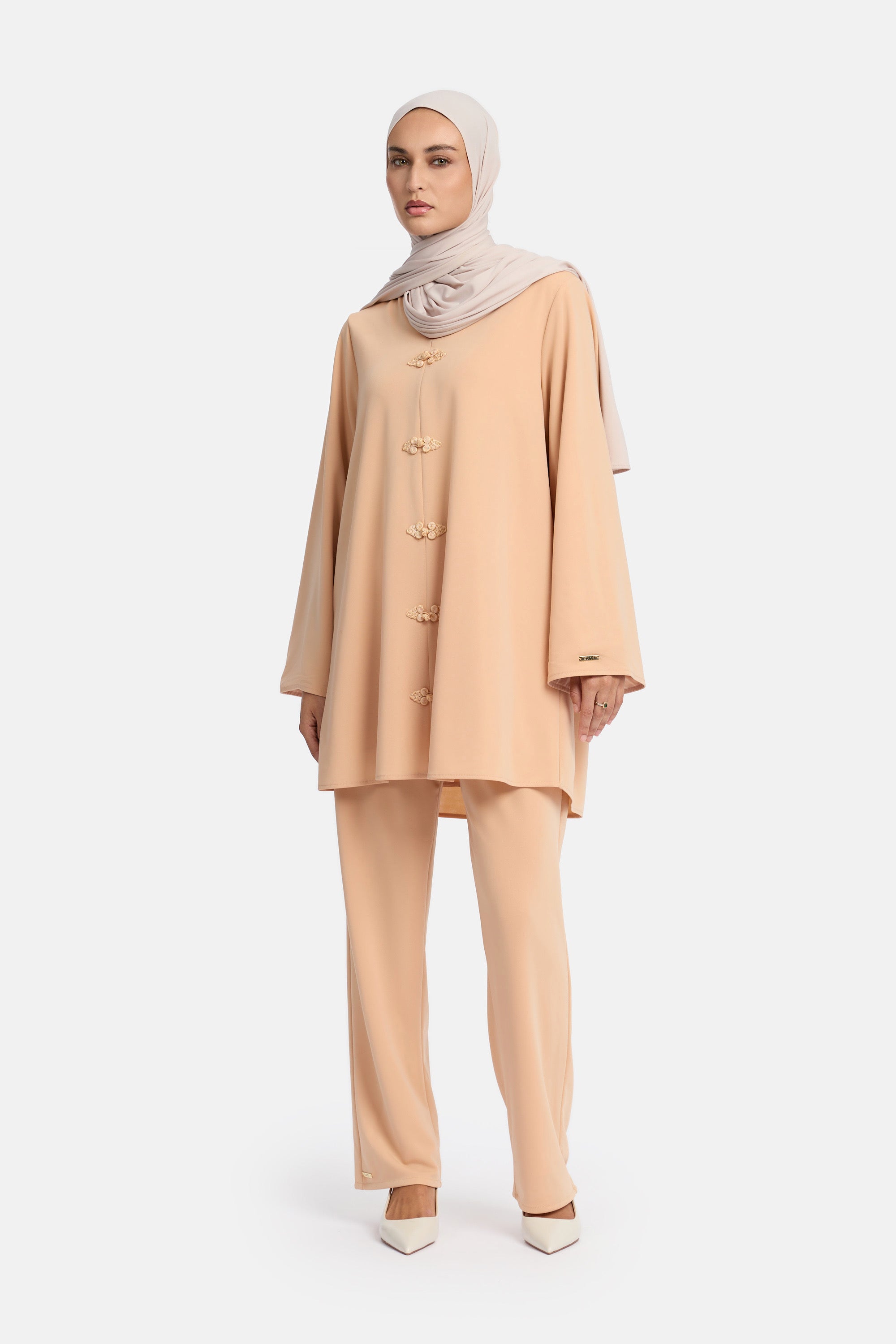 voor aanzicht van Model die draagt een modest kaftan set van het merk enti in de kleur pastel orange