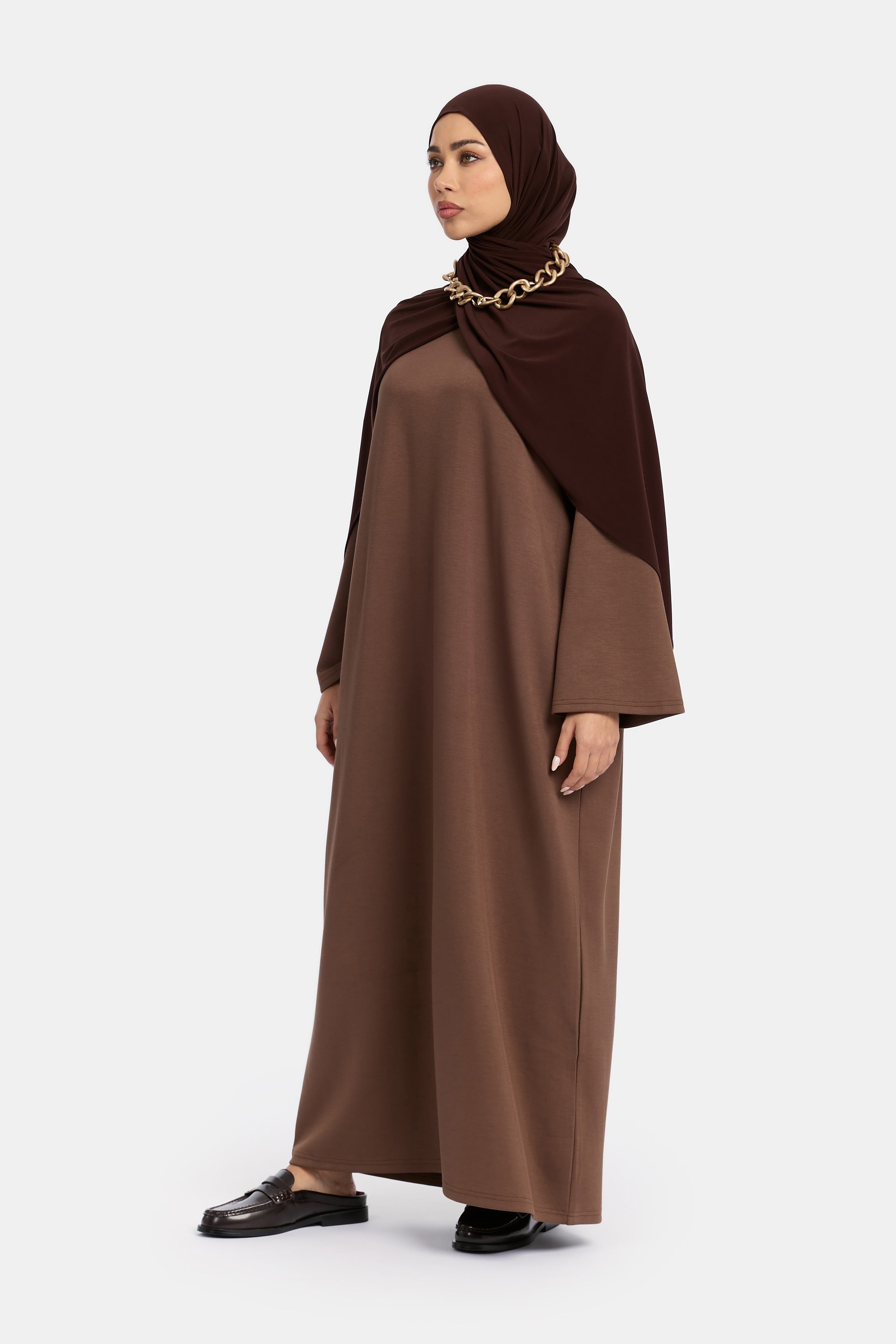 zij aanzicht van model die draagt Wide Sleeve Dress van het modest merk ENTI in de kleur donker bruin.