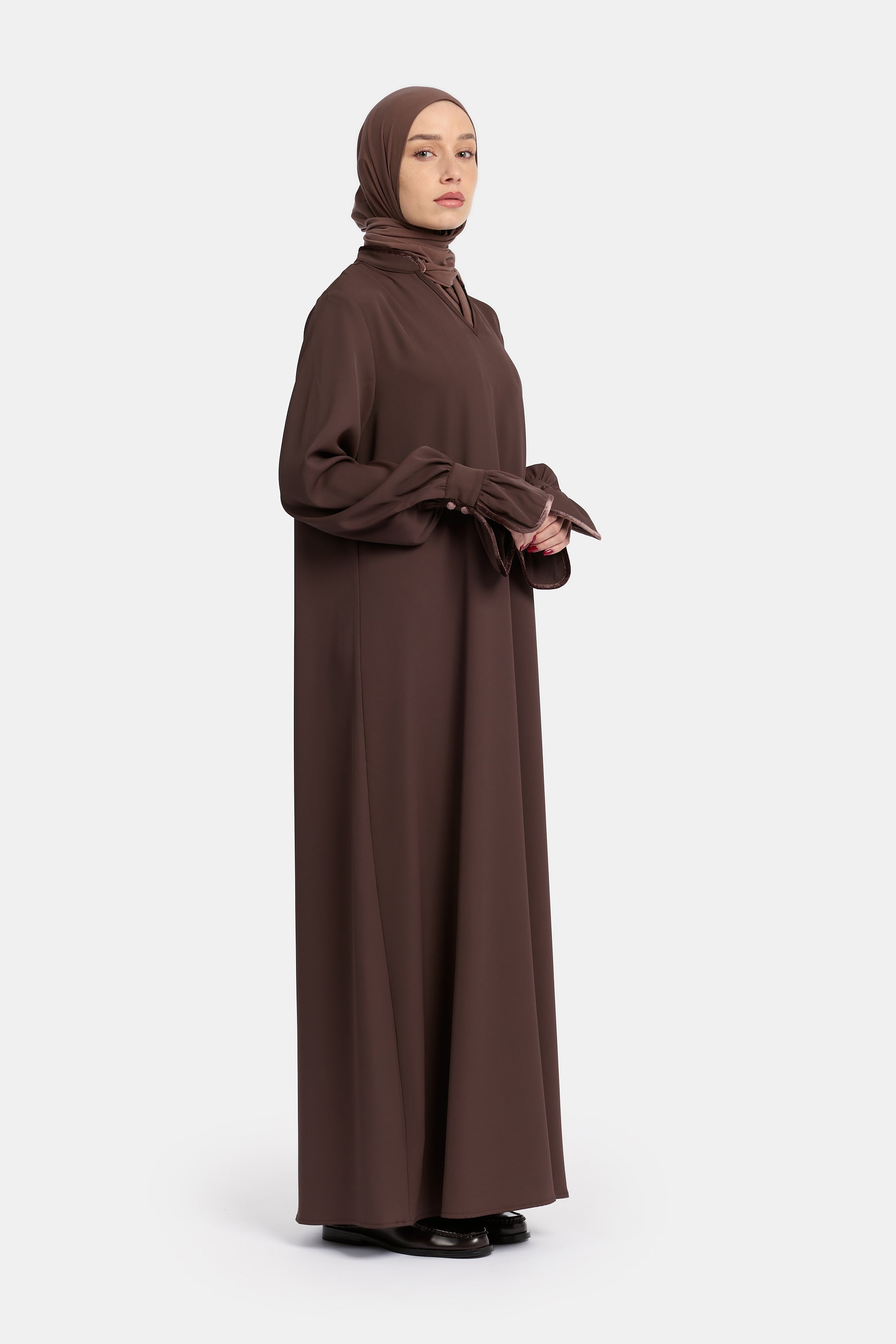 zij aanzicht van model die draagt de mastour velvet khimar en abaya set in de kleur donker bruin.