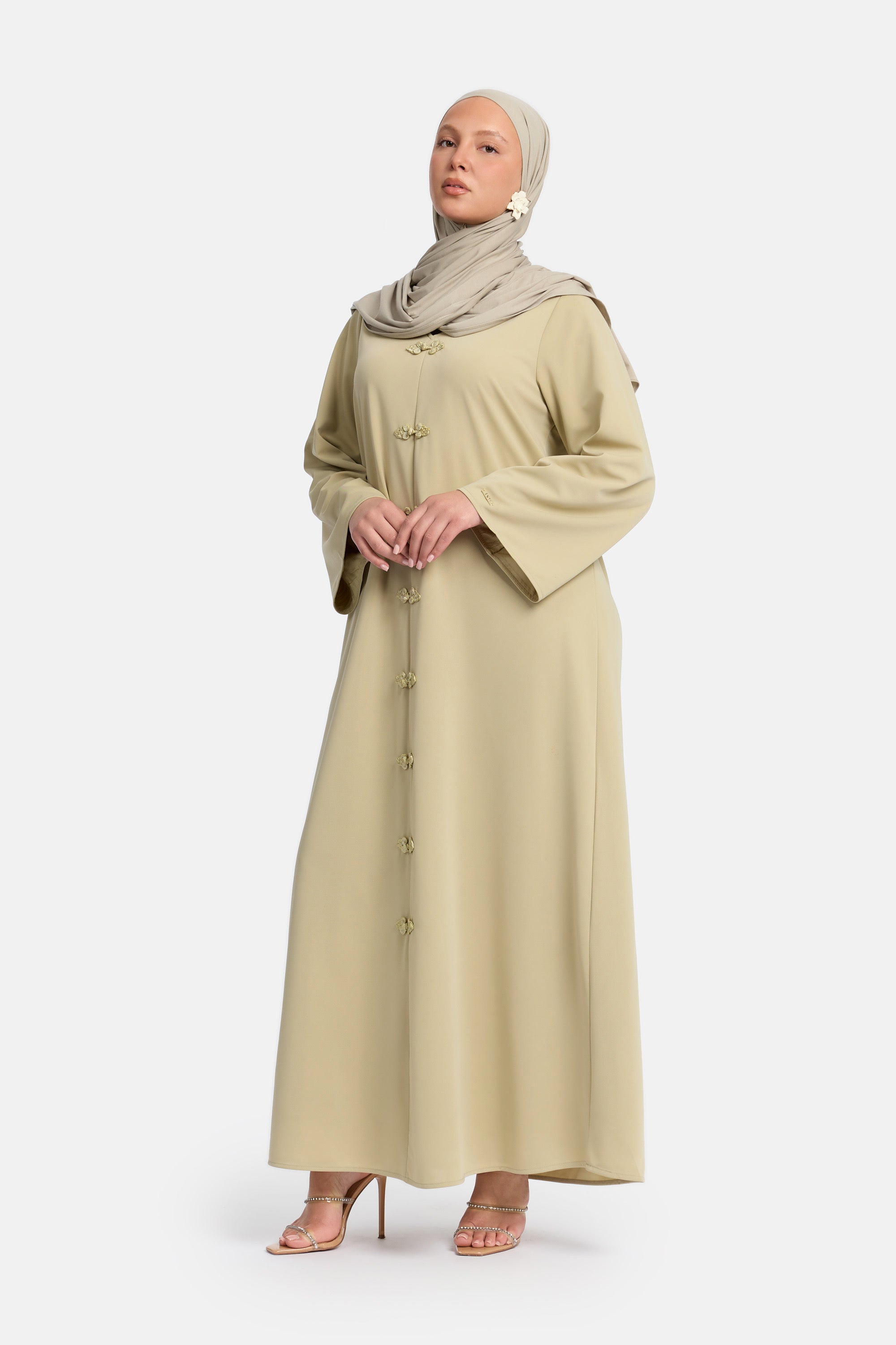 Zij aanzicht van Model die draagt een modest kaftan dress van het merk enti in de kleur soft green