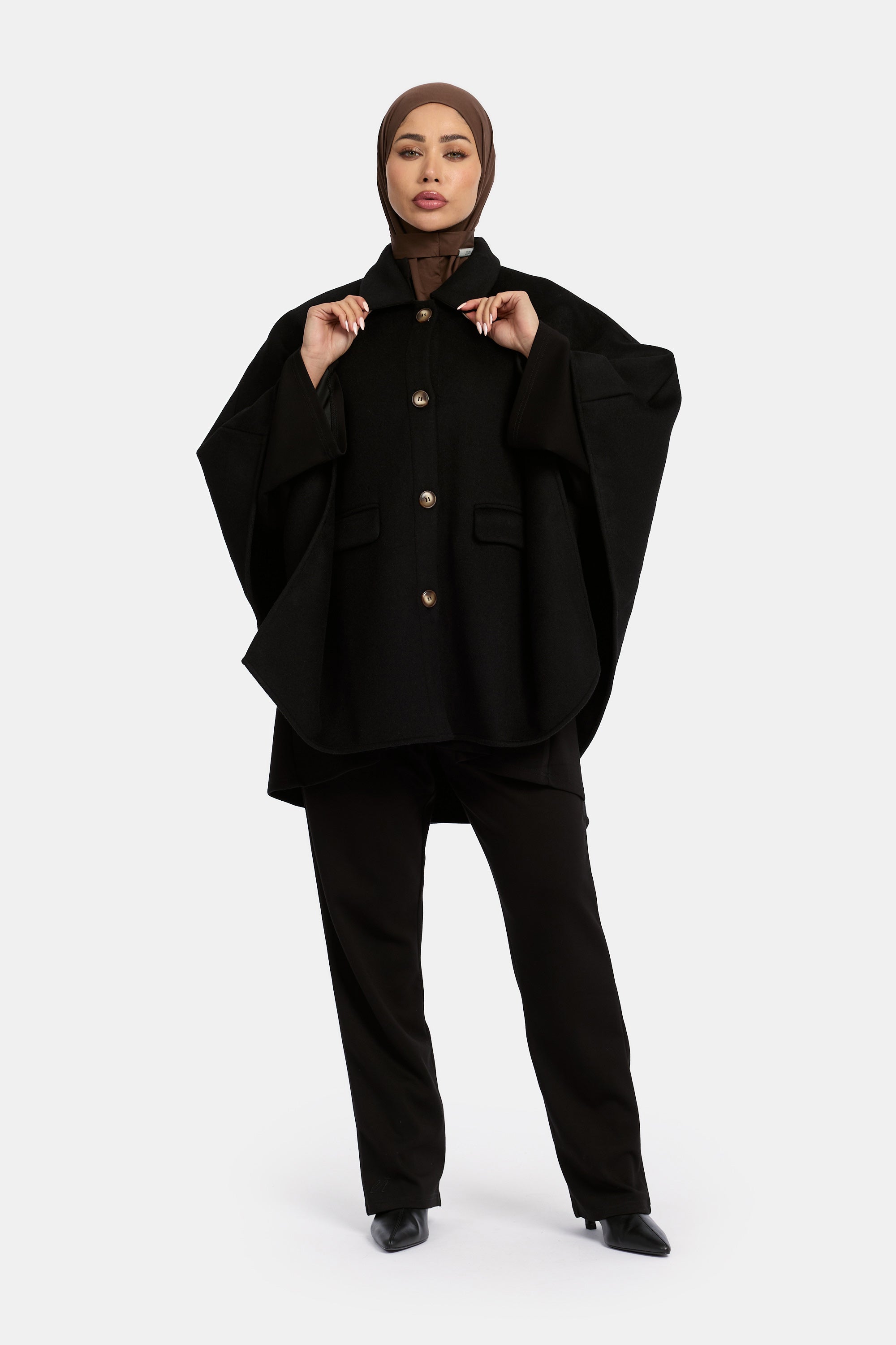 model draagt de wollen poncho van het modest merk enti in de kleur zwart